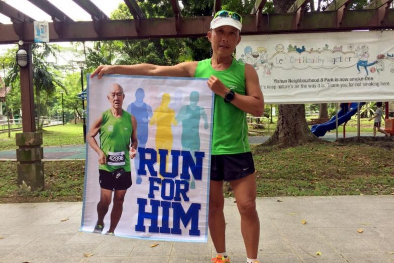 Sports trainer Ng See Chye holds a banner of his father