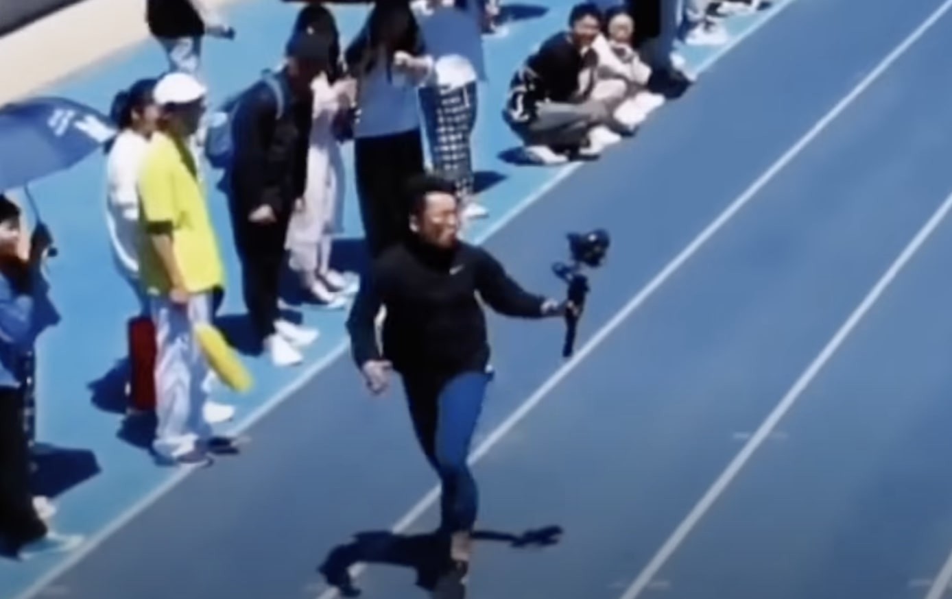 A university student in China serving as a Cameraman, beats sprinters to the line in 100m race